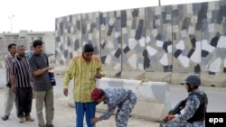 Iraqi police search civilians at a checkpoint in Ba'qubah. Security forces are still using the questionable bomb detector.