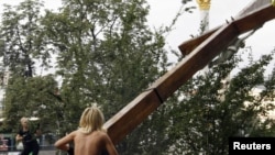 A Femen activist uses a chainsaw to cut down an Orthodox cross erected in memory of the victims of political repression under Soviet dictator Josef Stalin in Kyiv.
