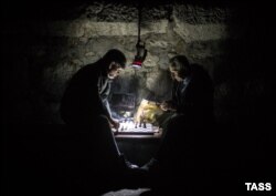 Men play chess during power cuts in Yalta, Crimea.