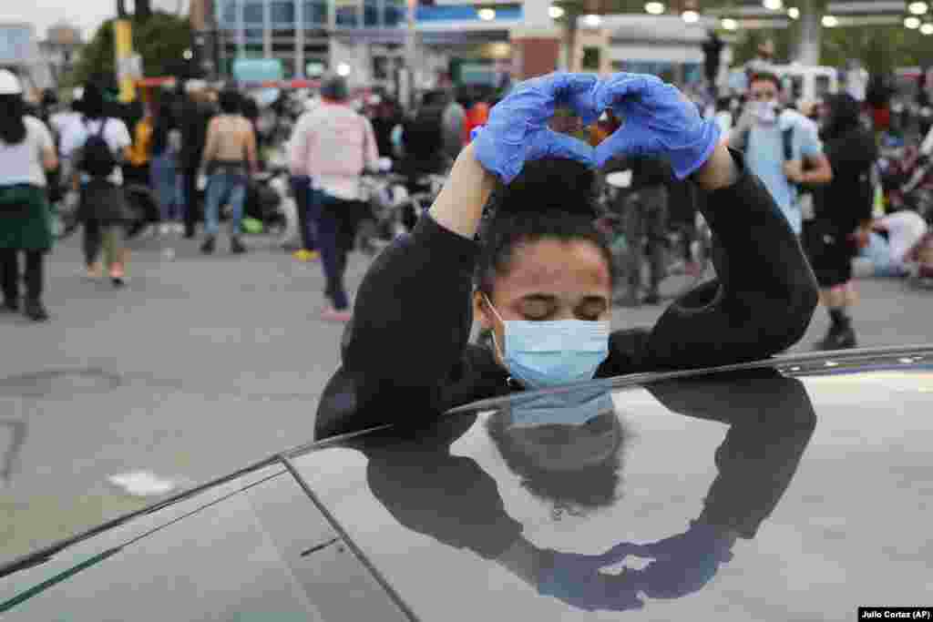 A demonstrator makes a heart sign while protesting after curfew Sunday, May 31, 2020, in Minneapolis.Protests continued following the death of George Floyd, who died after being restrained by Minneapolis police officers on Memorial Day. (AP Photo/Julio Cortez)