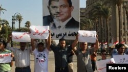 Участники протеста против правления Мухаммеда Мурси несут плакат с фотоколлажем из портретов Мурси и бывшего президента Египта Хосни Мубарака. Каир, 28 июня 2013 года.