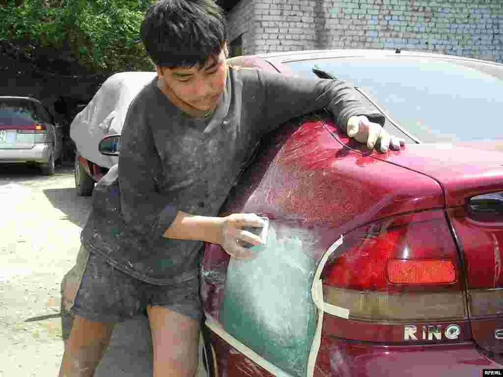 Another 15-year-old fixes a dent in a car in Almaty (RFE/RL) - Many working children are denied access to education. Those who try to continue attending school often fall behind and drop out, the International Labor Organization (ILO) reports.