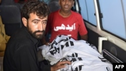 Abdul Majeed (left), brother of Shafqat Hussain, sits beside Hussain's body in an ambulance after his execution in Karachi on August 4.