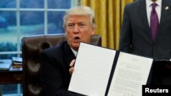 Președintele Donald Trump arătînd unul din ordinele sale executive