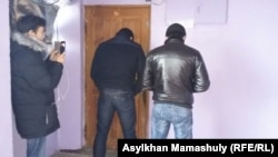 Полицейские, стоящие спиной, блокируют дверь в офис редакции оппозиционного сайта Nakanune.kz, где в это время происходит обыск. Алматы, 18 декабря 2015 года.