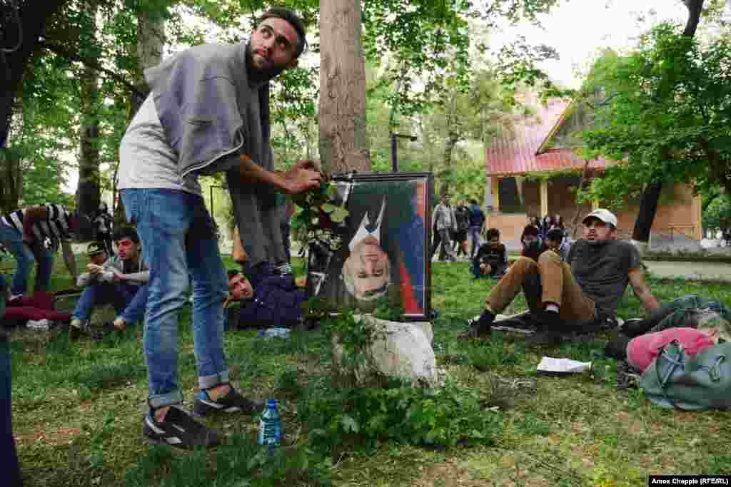 A man places a flower onto an upside-down portrait of Prime Minister Serzh Sarkisian in a children’s park in Yerevan. The frame features a black strip of cloth at the corner, traditionally placed over a portrait when someone is dead.