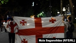 Protesters waive the Georgian flag near the parliament building in Tbilisi early on June 26.