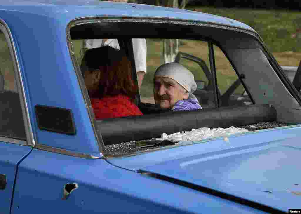 An old woman looks from inside a car with bullet holes and shattered windows as she flees fighting in the eastern Ukrainian town of Slovyansk on June 9. (Reuters/Gleb Garanich)