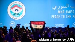 A man holds up a Syrian flag as attendees wait for the start of a plenary session at the Congress of Syrian National Dialogue in Sochi, January 30, 2018