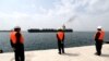 Workers watch a ship as it sails during an inauguration ceremony of new equipment and infrastructure at Shahid Beheshti Port in the southeastern Iranian coastal city of Chabahar, on the Gulf of Oman, on February 25, 2019.