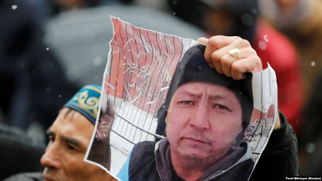 Участник одного из митингов в Алматы держит в руке фото активиста Дулата Агадила, погибшего при загадочных обстоятельствах в столичном СИЗО. 27 февраля 2020 года.