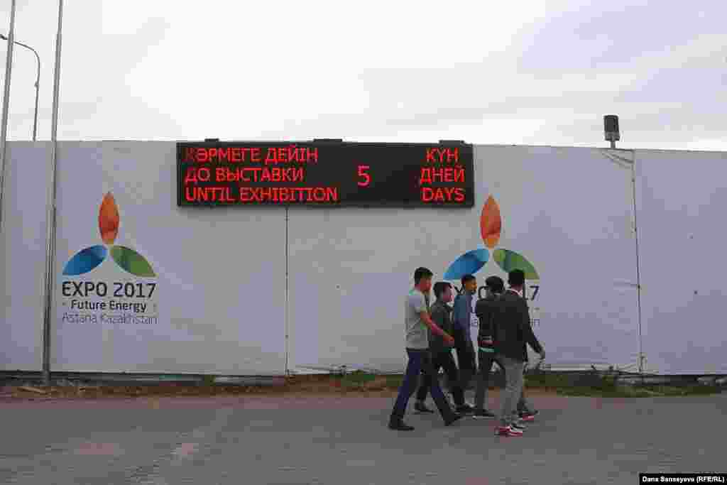 EXPO 2017 көрмесінің ашылуына қана күн қалғанын көрсететін электронды таблоның жанынан өтіп бара жатқан еріктілер.