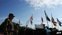 Pro-Russian militants stand guard at a checkpoint on the road between Luhansk and Donetsk, eastern Ukraine.