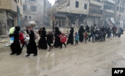 Syrian residents fleeing violence in the restive Bustan al-Qasr neighborhood arrive in Aleppo's Fardos neighborhood on December 13.