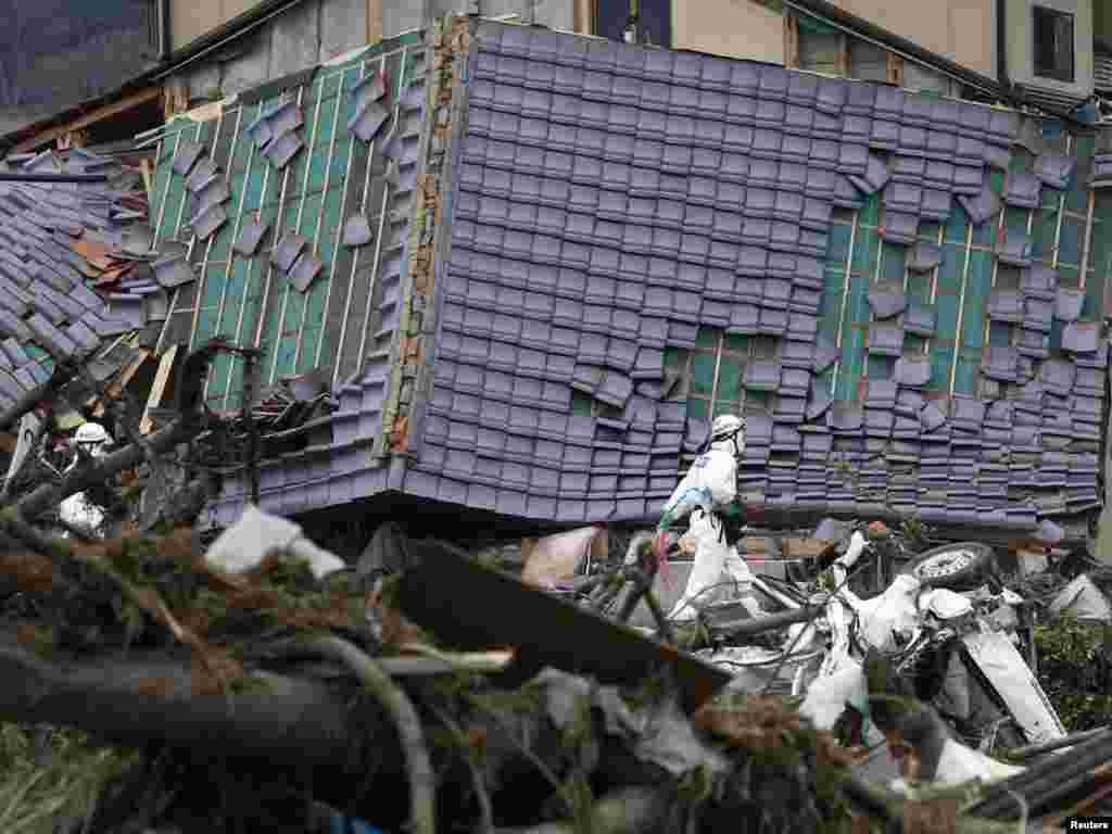 A Japanese police officer in a protective suit walks past a damaged house while searching for bodies in Minamisoma, about 18 kilometers from the damaged Fukushima nuclear power station on April 11. Photo by Kim Kyung-hoon for Reuters