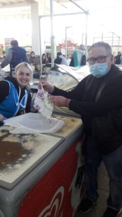 Балаклієць Юрій Грошев роздає маски Аліси Пономаренко на місцевому ринку