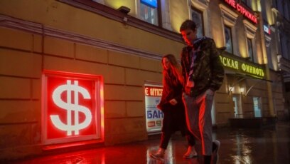 Prolaznici pored osvijetljenog znaka za američki dolar u Moskvi, mart 2020. 