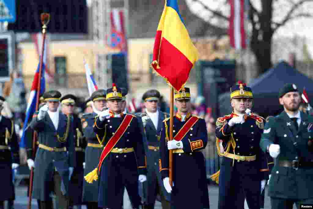Румунські офіцери у парадній формі урочисто несуть прапор Румунії