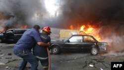 Një person e ndihmon zjarrfikësin për ta shuar zjarrin në një makinë nga eksplodimi i fuqishëm që ndodhi sot në Bejrut të Libanit