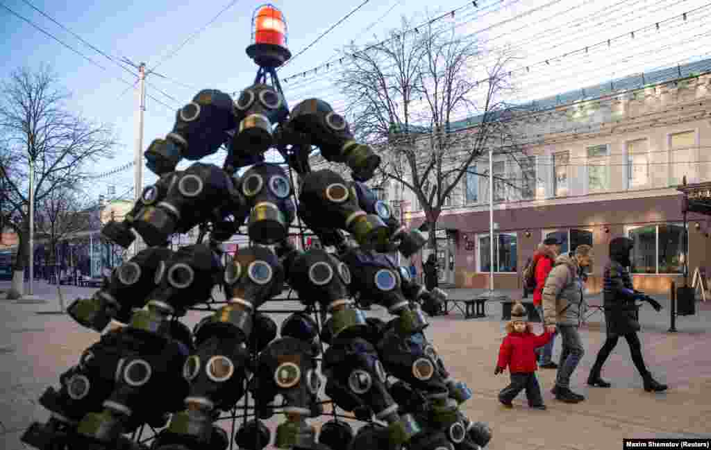 People walk past a Christmas tree made of gas masks in Ryazan, December 12, 2020. 