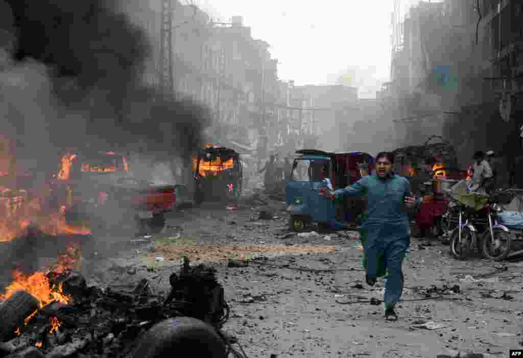 A Pakistani man runs past burning vehicles at the site of twin bomb explosions at the busy Kissa Khwani market in Peshawar on September 29, 2013. 