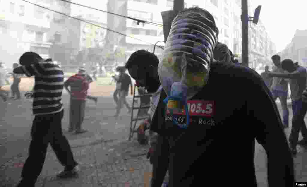 A supporter of ousted Egyptian President Muhammad Morsi wears a makeshift gas mask as others run away from shooting during clashes on Ramses Square in Cairo on August 16. (Reuters/Amr Abdallah Dalsh)
