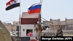 SYRIA -- A Russian soldier places the Russian national flag at the Abu Duhur crossing on the eastern edge of Idlib province, September 25, 2018