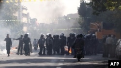 Iran -- Iranian riot police stand next to a garbage container which is set on fire by protesters in central Tehran, near the main bazaar, 03Oct2012 