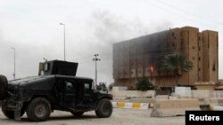 Smoke from previous clashes with Islamic State militants rises from a building near an Iraqi security forces military vehicle during an intensive security deployment in Ramadi, west of Baghdad, in December.