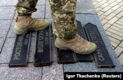 A Ukrainian soldier steps on signs that used to point in the direction of Russian cities that were removed from use in Odesa amid Moscow's invasion of Ukraine on April 14.