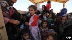 Iraqi women and children who fled the towns of al-Shirqat and Qayyarah during reported fighting between Iraqi government forces and militants from the Islamic State extremist group are transferred to a camp for displaced people in late July.