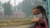 A girl wearing a protective mask looks out from her balcony in the village of Beloomut, near Moscow, during serious forest fires caused by a heat wave in 2010. 