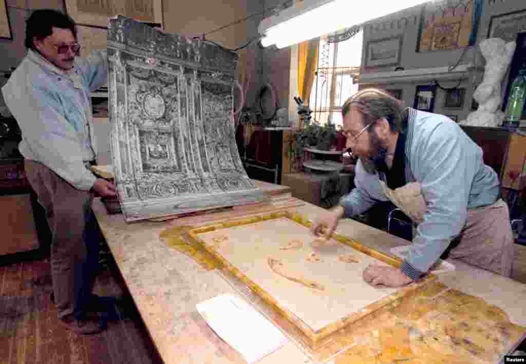 A craftsman uses a historic photo for reference during the reconstruction. Work to replicate the Amber Room took 24 years. 