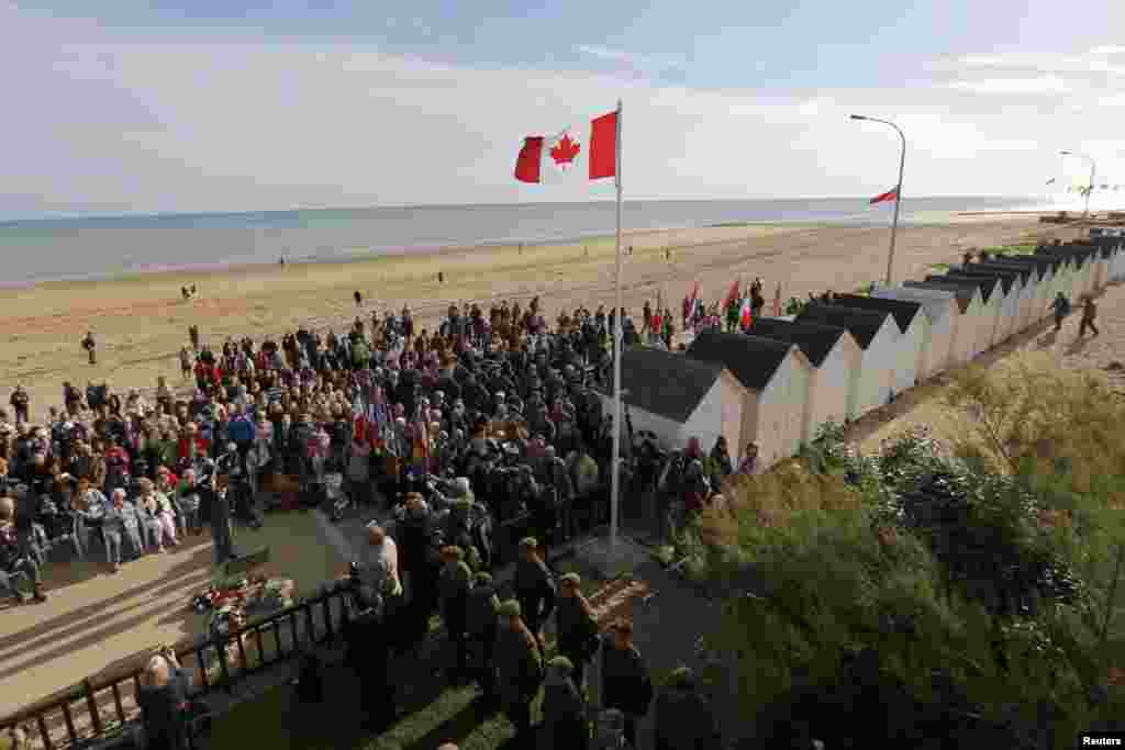 Family members of Canadian D-Day veterans, currently-serving soldiers, and local citizens attend a ceremony outside The Queen's Own Rifles of Canada House in Bernières-sur-Mer.