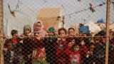 SYRIA -- Displaced Syrian children stand behind a fence outside their tents a camp set up near the village of Kafr Lusin, in Idlib's northern countryside near the Syria-Turkey border, October 22, 2019