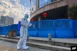Рабочий в защитной одежде и с дезинфицирующим оборудованием выходит из центральной больницы «Ухань» в Ухане, Китай, 6 февраля 2021 года