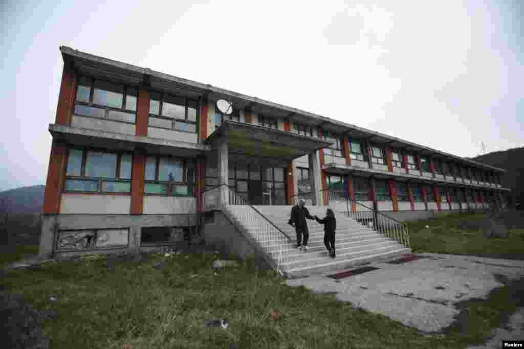 Drazen Matovic, 36, greets a friend on the steps of an abandoned primary school in the village of Strmica, which serves as a makeshift refugee camp for ethnic Serb returnees.