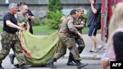 Пророссийские боевики несут тело погибшего во время нападения на пограничный командный центр в окрестностях Луганска, 2 июня 2014 года. 