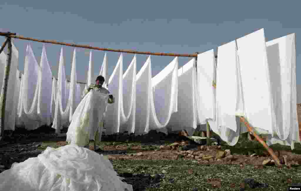 A laundryman folds up sheets of cloth after drying them in an open area on the outskirts of Lahore, Pakistan. (Reuters/Mohsin Raza)