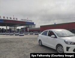 Родственники ждут водителя машины у блокпоста при выезде из Кучара. Надпись на транспаранте: "Горячо поздравляем с 70-летием со дня создания КНР!"