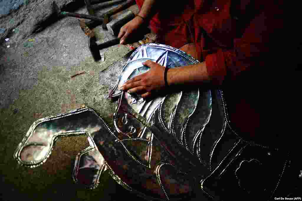 A metal worker hammers texture into a horse decoration destined for a truck in Rawalpindi. 