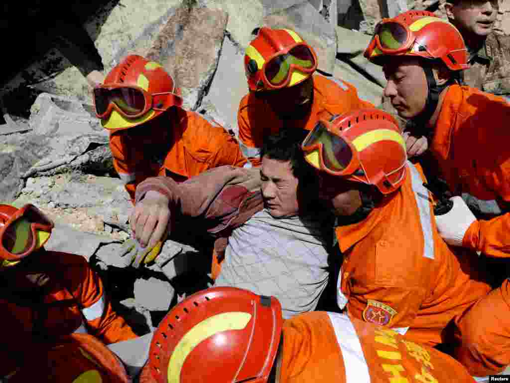 Rescue workers carry an injured man from the ruins after a devastating earthquake in China's Qinghai Province. Nearly 800 people have died in the disaster. Photo by Reuters