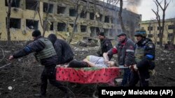 Рятувальники і волонтери несуть вагітну жінку, яка постраждала внаслідок авіаудару російських військових по пологовому будинку і дитячій лікарні в Маріуполі, 9 березня 2022 року