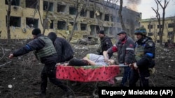 Salvatori și voluntari ucraineni transportă o femeie însărcinată rănită într-un atac rusesc asupra maternități și spitalului pentru copii din Mariupol, 9 martie 2022