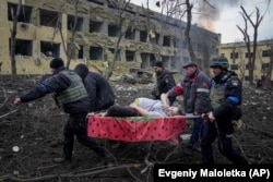 Українські рятувальники і волонтери несуть вагітну Ірину Калініну, яка постраждала в результаті авіаудару військ РФ по пологовому будинку та дитячій лікарні в Маріуполі, 9 березня 2022 року. Згодом жінка та її дитина померла