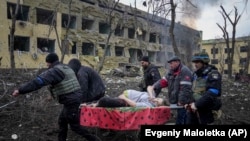 Punëtorët ukrainas të emergjencës dhe vullnetarët duke e bartur një shtatzënë të plagosur nga sulmi rus në një maternitet në Mariupol. 9 mars 2022.

