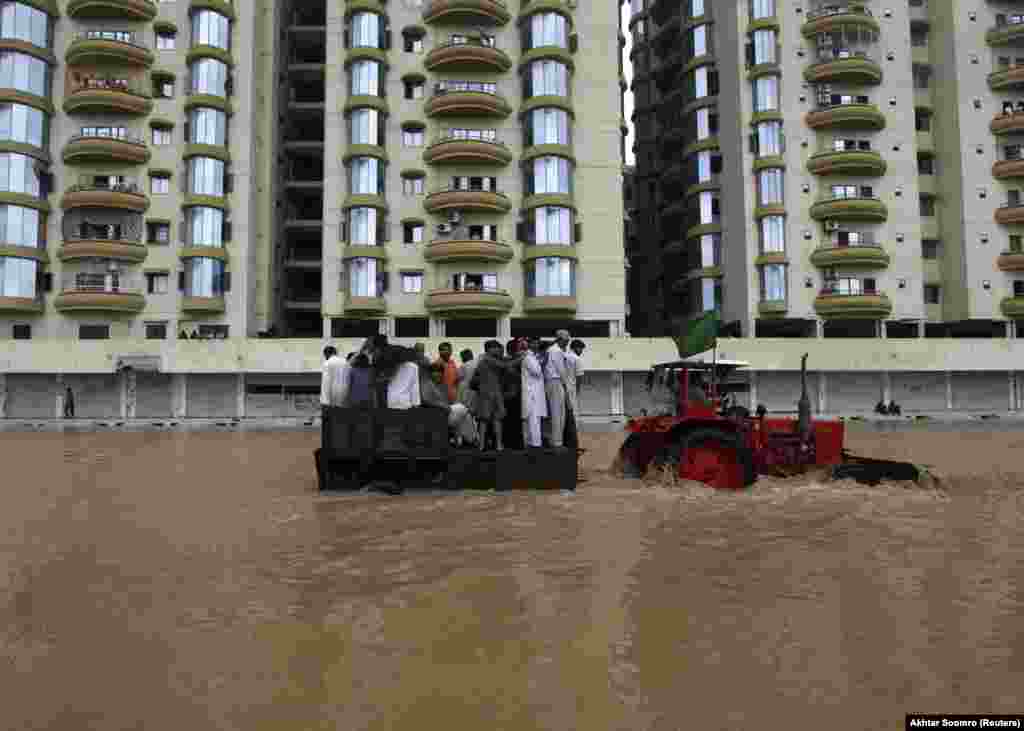 A tractor tows residents through floodwaters to a safe place on the outskirts of Karachi on August 4. Monsoon rains across Pakistan killed more than 100 people and affected hundreds of thousands.