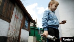 A boy holds the remains of a mortar shell which hit a residential building in a village outside the separatist-held city of Donetsk in the Donbas region, where fighting has reportedly intensified in recent days.