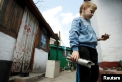A boy holds the remains of a mortar shell which hit a residential building in a village outside the separatist-held city of Donetsk in the Donbas region, where fighting has reportedly intensified in recent days.