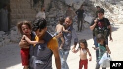 Сирийские мужчины несут детей среди обломков разрушенных зданий после воздушных ударов по повстанцам в районе Аль-Мешхед в Алеппо, 25 июля 2016 года 